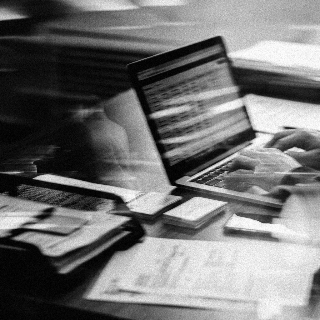 A business owner entering a client into the system at a laptop, business cards and papers beside the keyboard.