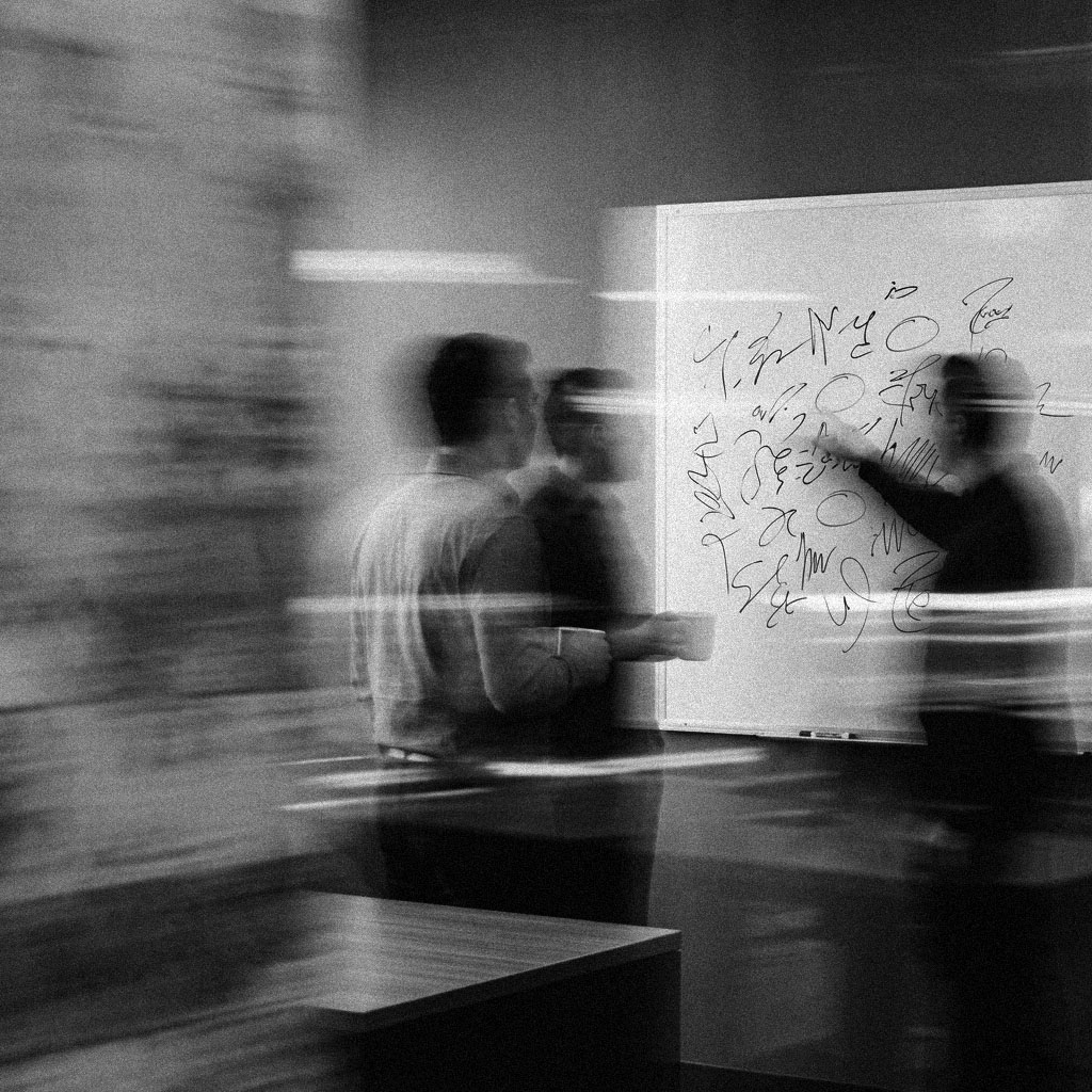 Coworkers at a whiteboard during a weekly standup meeting.